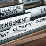 3D illustration of a folder, focus on a tab with the word infringement. Conceptual image of copyright law