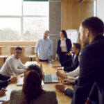 Brainstorming in modern loft office. Group of business people in big office have meeting and discussing company stats and sheets. Multiethnic coworkers discussing over new business project.