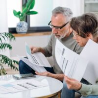 Elderly couple checking documents with tax and internal bills, making payments and discussing budget. Family calculating funds for purchase new home or car.