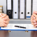 Hands of wife and husband signing divorce documents or premarital agreement at the lawyer's office Hands of wife and husband signing divorce documents or premarital agreement at the lawyer's office