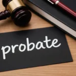 Gavel sits by black card with word probate handwritten. Notebook and pen nearby suggest legal estate matters. Court decision planning for inheritance.